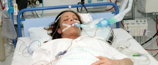 Patient som ligger i en hospitalsseng og er tilsluttet en respirator.